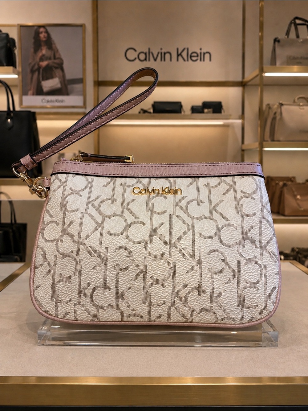 Calvin Klein wristlet in cream with repeating logo pattern. Pink leather trim